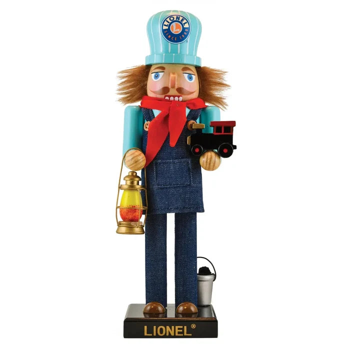 A collectible Lionel nutcracker figurine featuring a cartoonish character in blue overalls and a red tie, holding a miniature train, with a brown hat and mustache, standing on a black base with the brand name 'Lionel' visible.
