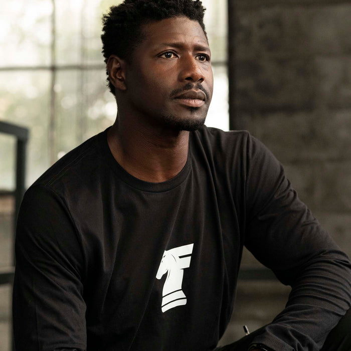 Man wearing Workhorse's Classic Long Tee in black, sitting indoors.