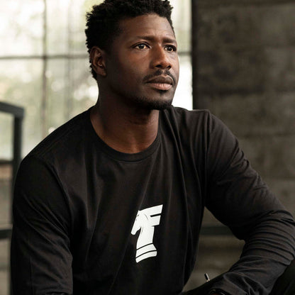 Man wearing Workhorse's Classic Long Tee in black, sitting indoors.
