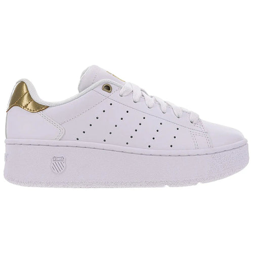 A white sneaker is positioned sideways showing its smooth design and gold accents on the heel The sneaker has a thick sole with ventilation holes along the sides