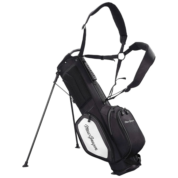 A black and white golf bag stands upright with extending legs and shoulder straps designed for carrying. It features multiple zippered pockets and a prominent brand name on the side.