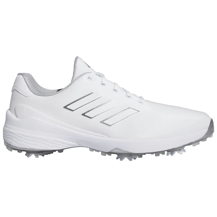 A white athletic shoe features three silver stripes on the side with a textured upper and a rubber sole equipped with small spikes designed for traction on grass or turf surfaces.