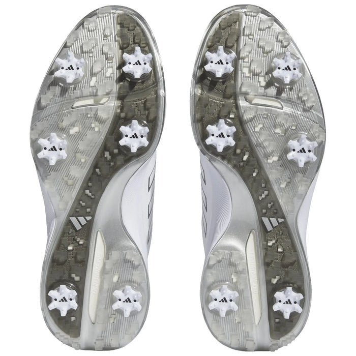 Two athletic shoes viewed from the bottom show a patterned gray outsole with six white cleats each designed for traction on grass or turf fields.