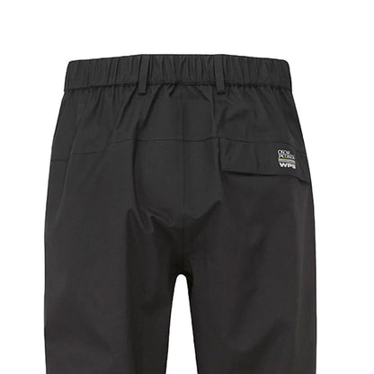 Black waterproof pants hang vertically showcasing their elastic waistband and a rear pocket with branding near the top edge in a simple undisturbed setting