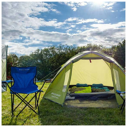 A green tent is set up in a grassy area with a blue camping chair nearby sunlight brightens the scene and clouds float in the sky above surrounding trees create a natural backdrop.
